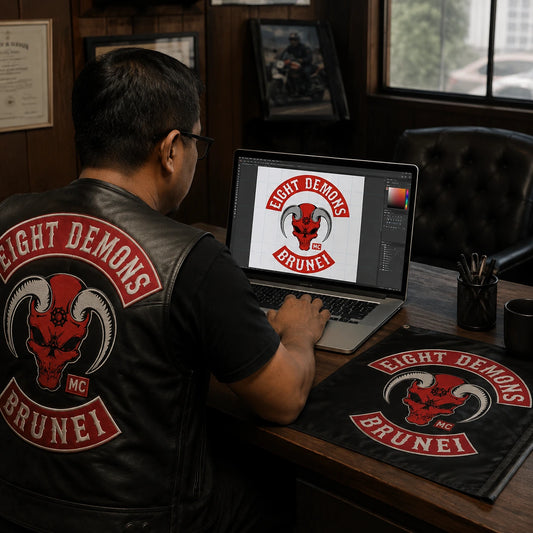 A motorcycle club secretary prepares an approved club logo file beside a physical flag reference.
