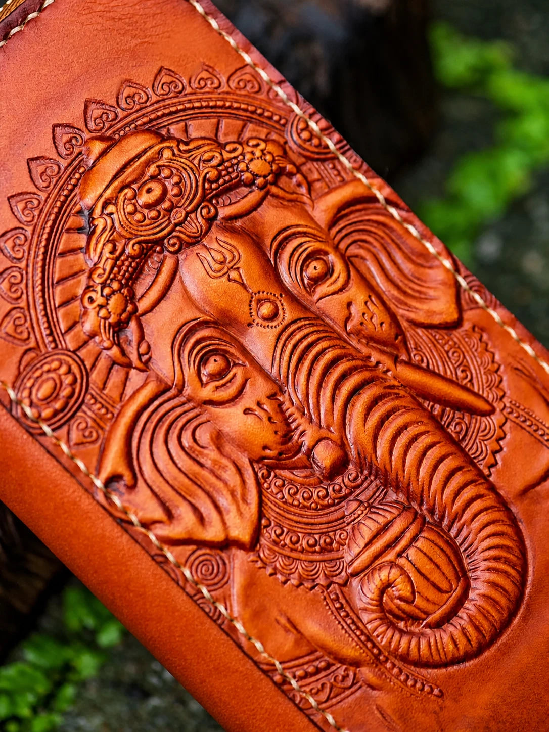 close-up Ganesha relief carving on red-brown leather wallet