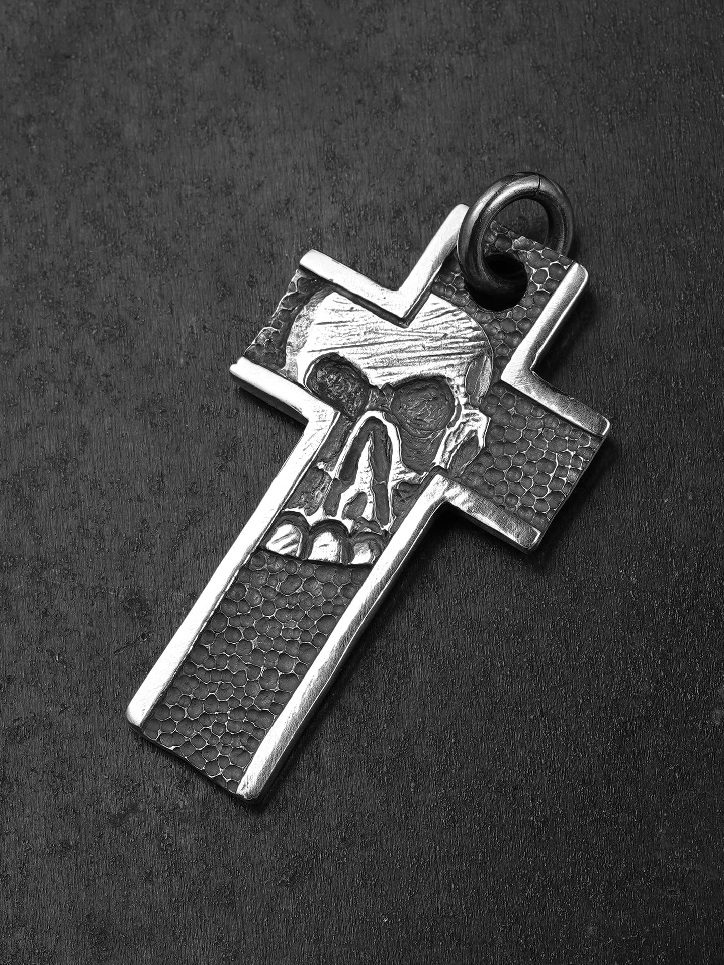 Angled view of hammered skull cross silver pendant