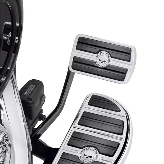 Chrome skull brake pedal pad installed with matching footboard on a Harley Softail
