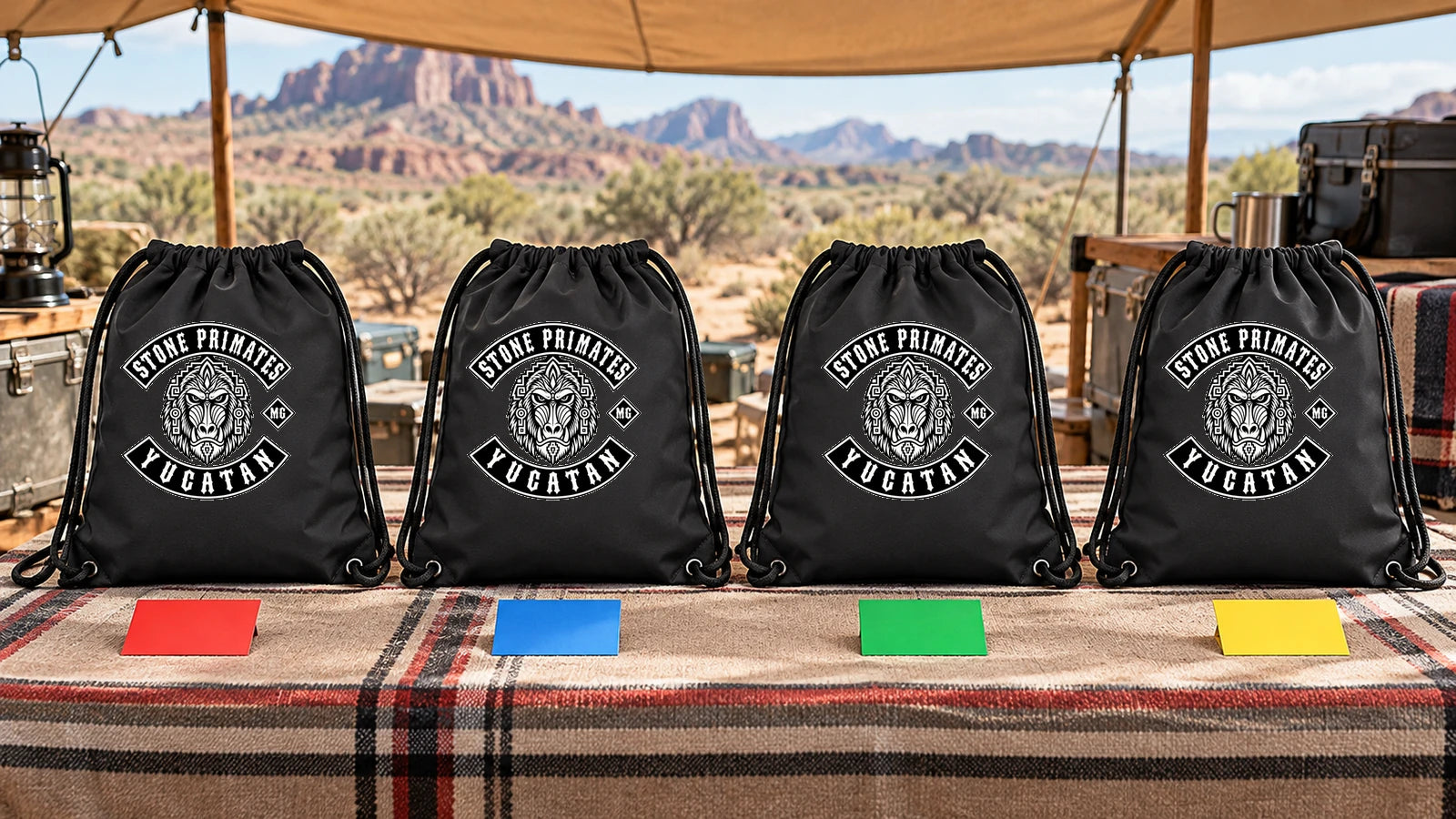 Four Stone Primates Yucatan logo drawstring bags separated into private motorcycle-club gear zones at a desert camp table