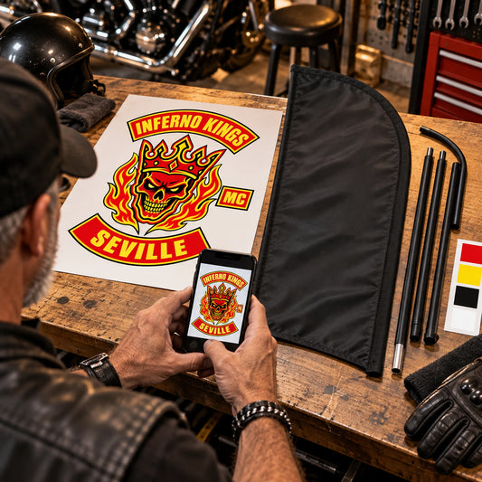 Send Your Club Artwork: custom motorcycle club feather flag shown in mature rider photographing an authorized club emblem on a clean garage workbench.