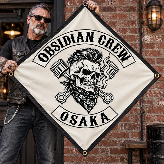 A leather-vested rider displays a fully visible custom diamond-shaped club flag against a brick clubhouse wall.