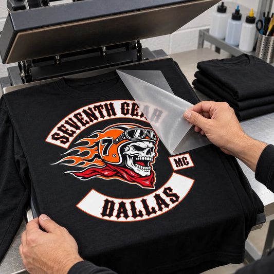 Print operator peeling DTF transfer film from a detailed multicolor motorcycle club design on a black long-sleeve shirt.