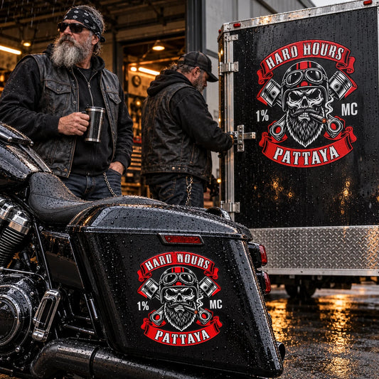 Road captain and mechanic beside a rain-damp support trailer and pannier carrying durable custom vinyl club stickers.