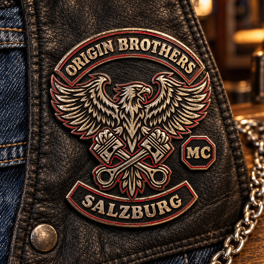 Old-school ORIGIN BROTHERS antique metal club pin on black leather and denim beside a silver chain.